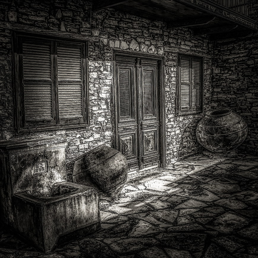 Black and white stone courtyard with wooden shutters and ancient jars