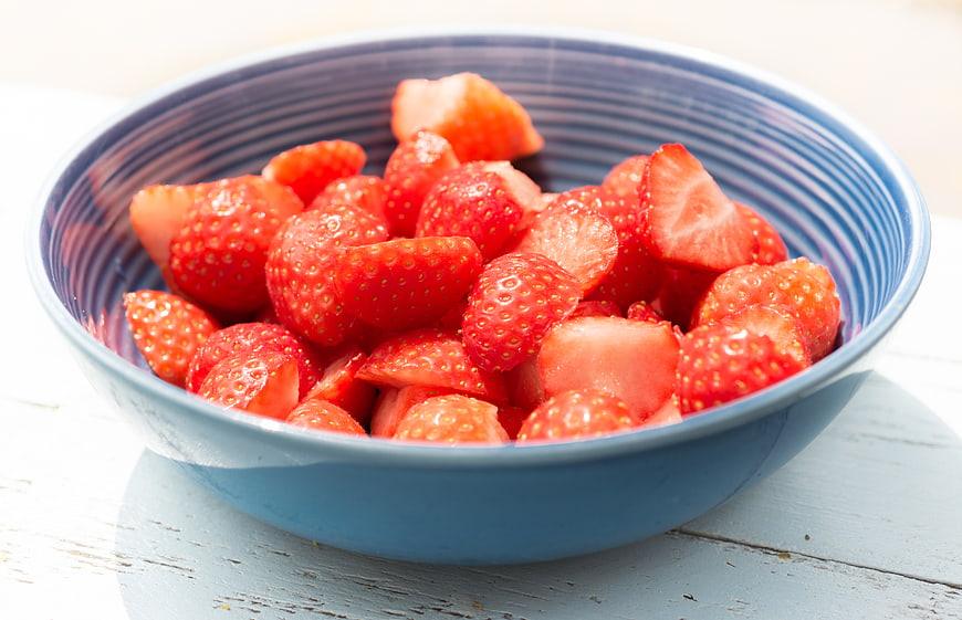 Fresh sliced strawberries in a blue ceramic bowl
