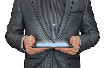 Businessman in gray suit holding glowing tablet computer