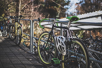 Black and green road bike parked at outdoor rack