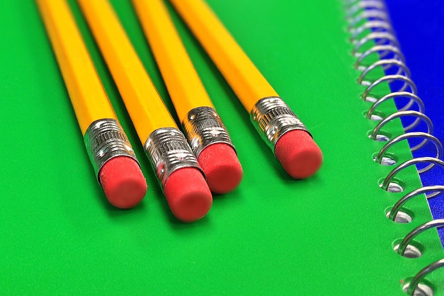 Yellow Pencils and Spiral Notebook on Green Background