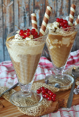 Two iced coffee parfaits with whipped cream, red currants, and wafer sticks