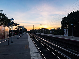 Empty Train Station Platform at Sunset with Tracks
