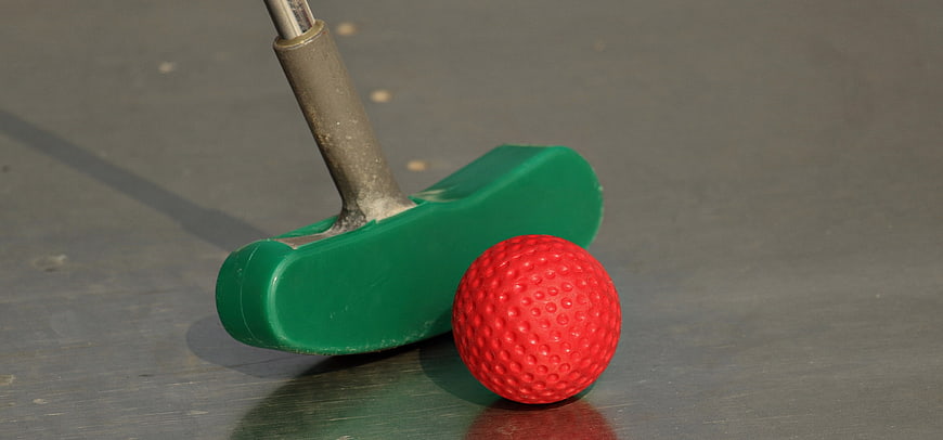 Green Mini Golf Putter And Red Ball On Gray Surface