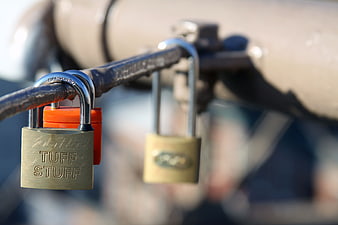Close-up of Brass and Orange Padlocks on Bicycle Handlebars