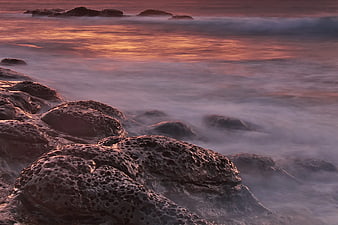 Long Exposure Sunset on Rocky Coastline with Misty Waves