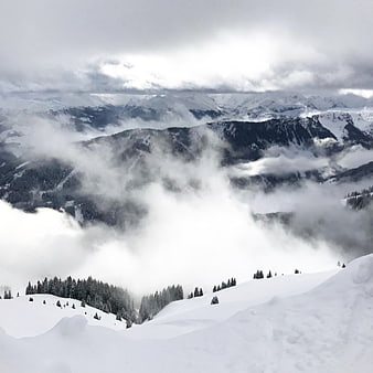 Snowy mountain landscape with clouds and pine trees