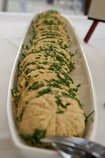 Sliced herb butter roll with chives on white platter