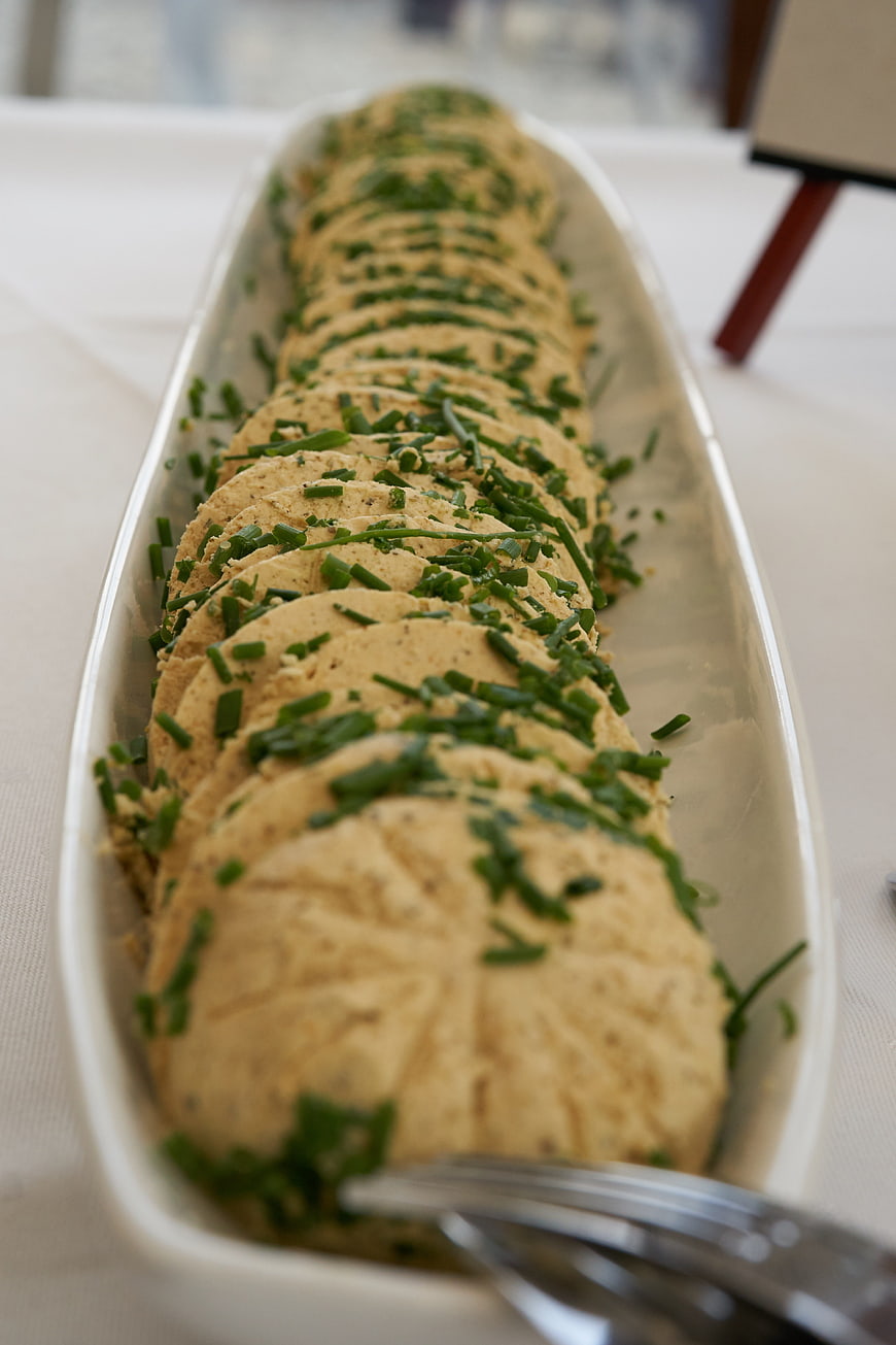 Sliced herb butter roll with chives on white platter