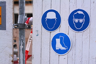 Blue safety signs on white wooden construction fence