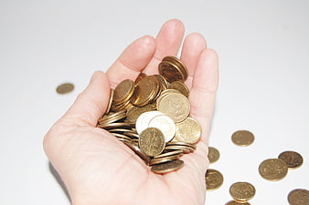 Hand holding pile of gold and silver coins on white background