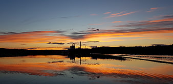 Panoramic sunset over river with industrial silhouette