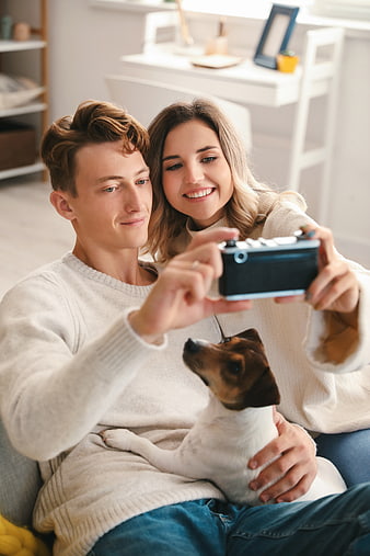 Happy couple taking selfie with dog at home