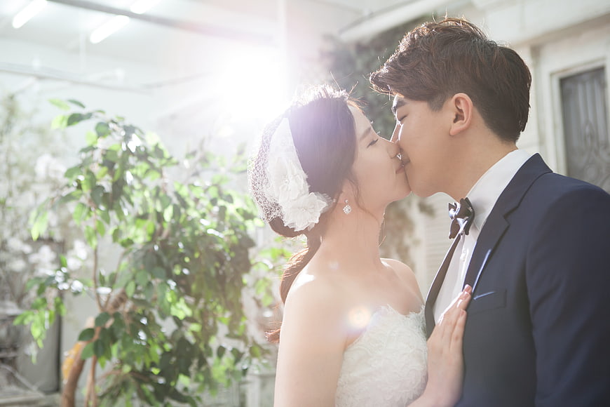 Romantic wedding couple kissing in sunlight