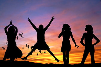 Silhouettes of four women jumping and posing against sunset sky