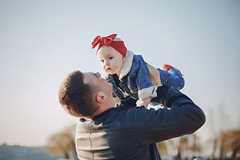 Father lifting baby daughter in denim outfit outdoors