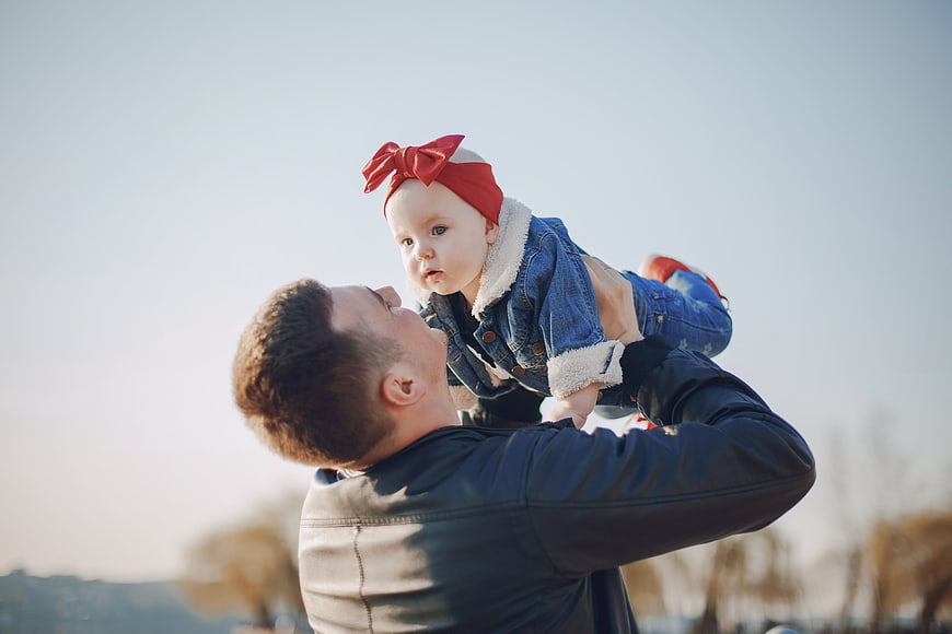 Father lifting baby daughter in denim outfit outdoors