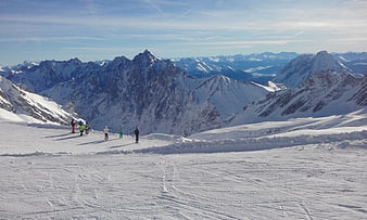 Skiers on Snowy Mountain Slope with Alpine Peaks