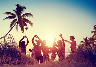 Friends dancing on tropical beach at sunset