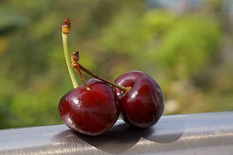 Two Fresh Red Cherries on Metal Surface