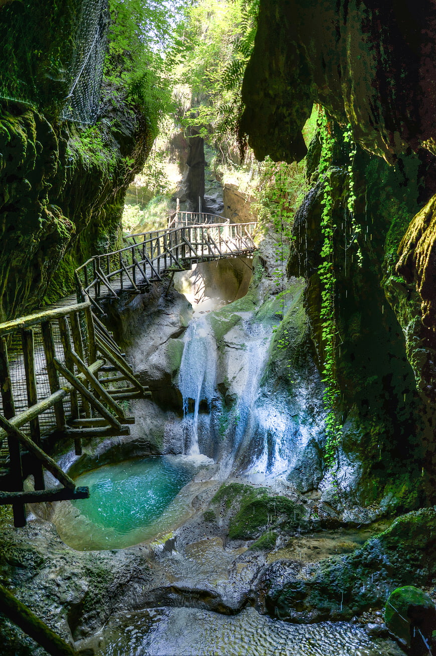 Lush tropical waterfall with wooden walkway in forest canyon