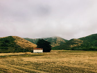 Solitary white house in misty mountain valley landscape