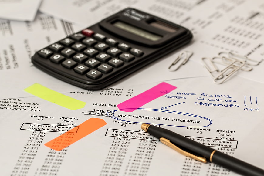 Financial documents with calculator, pen, and sticky notes on desk