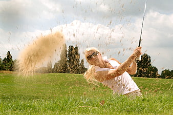 Woman Golfer Swinging Club in Sand Bunker