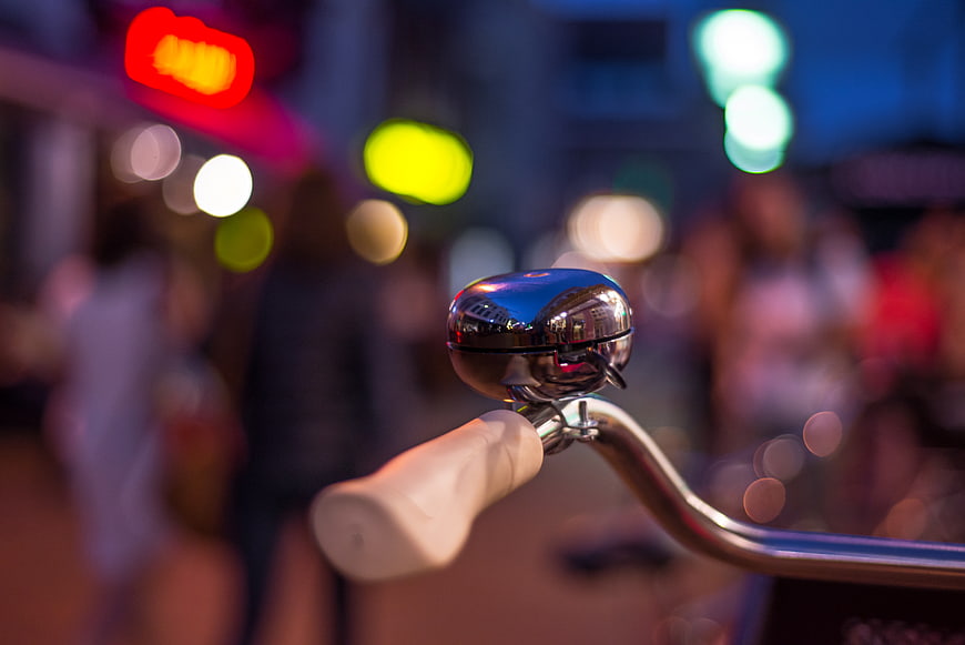 Close-up of bicycle bell with colorful city bokeh background