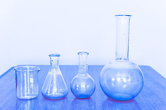 Glass Laboratory Beakers and Flasks on Blue Surface