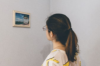 Woman with glasses looking at framed art on wall