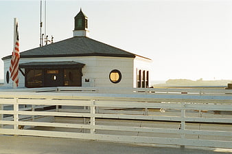 White Pier Building with American Flag and Wooden Railing