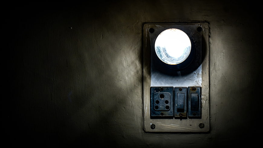 Vintage industrial light fixture with switches on dark wall