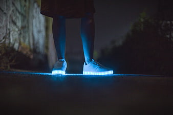 Glowing LED sneakers on legs at night outdoors