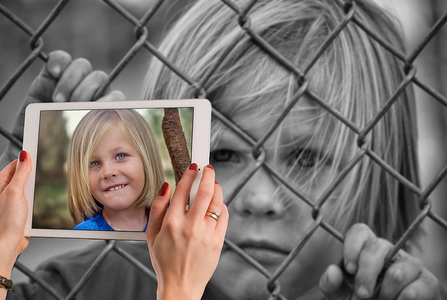 Child Behind Fence Holding Tablet With Colorful Photo