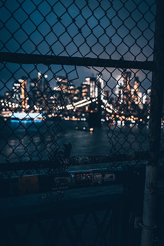 City skyline at night through chain link fence