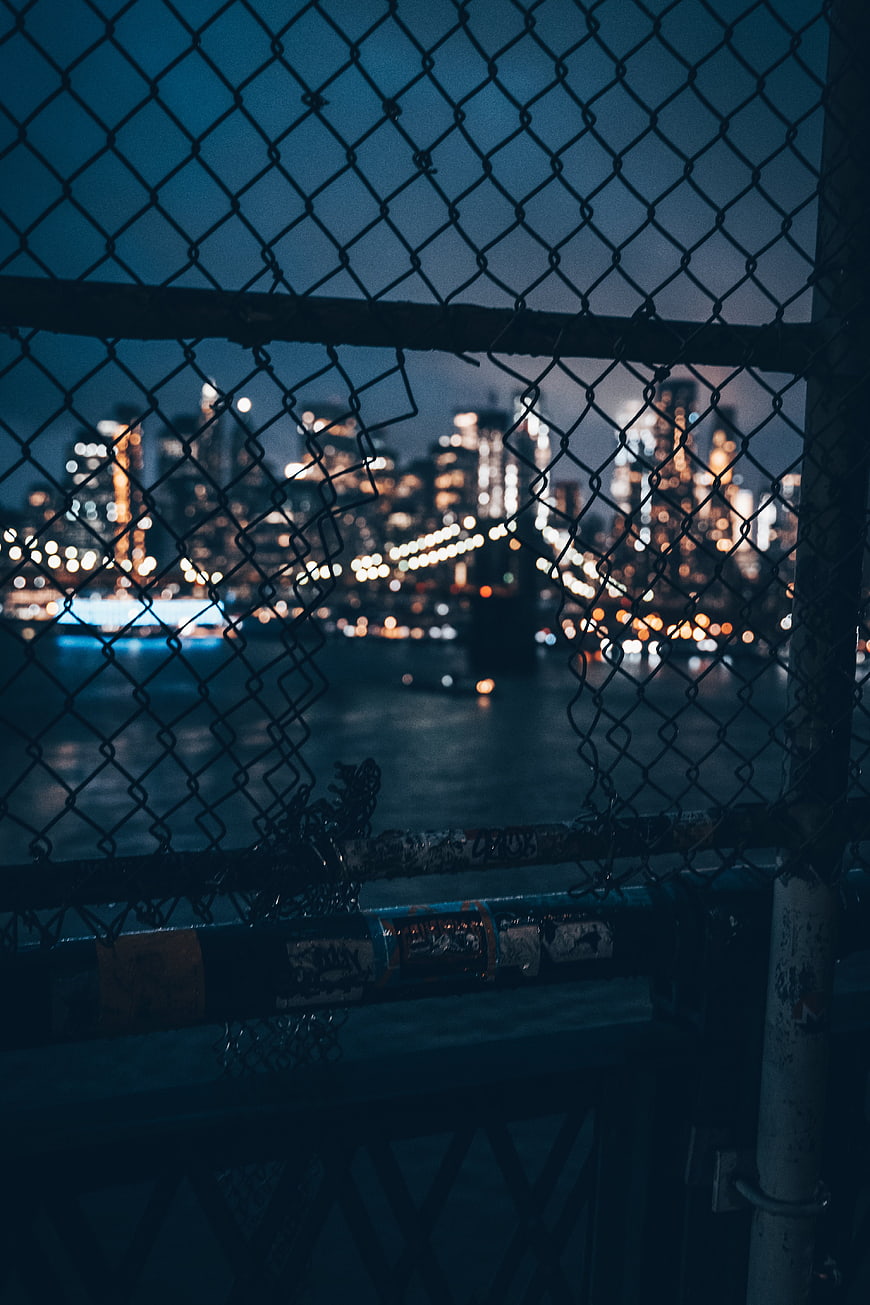 City skyline at night through chain link fence