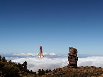 Space Shuttle Launching Above Clouds in Mountain Landscape