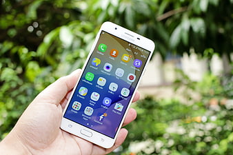Hand holding white Samsung smartphone outdoors