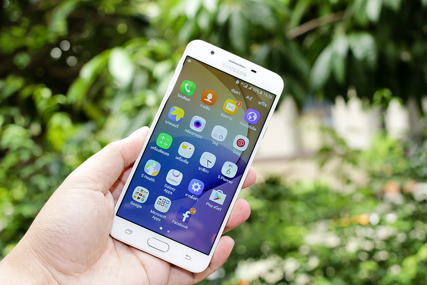 Hand holding white Samsung smartphone outdoors
