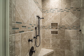 Modern beige tiled shower with black fixtures and bench