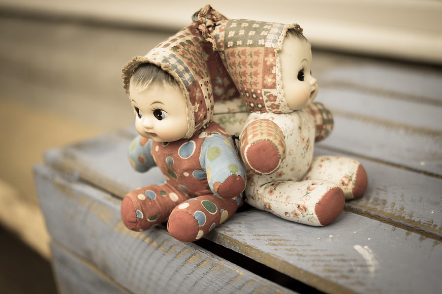 Vintage cloth dolls sitting on rustic wooden bench