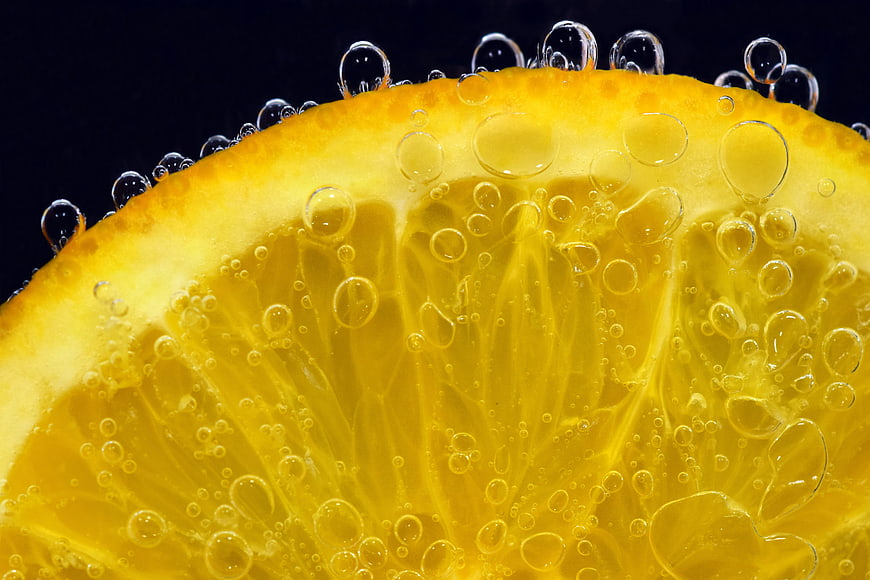 Close-up of a lemon slice submerged in carbonated water with bubbles