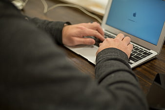 Close-up of hands typing on a laptop keyboard at a desk