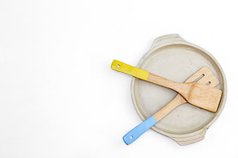 Top view of wooden spatulas in ceramic baking dish on white background