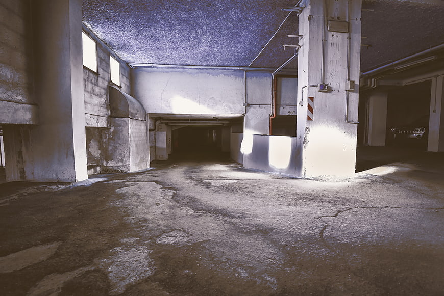 Empty concrete parking garage with dramatic sunlight and shadows