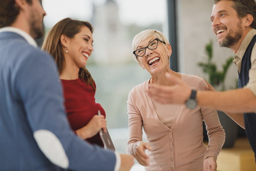 Happy senior woman laughing with colleagues in office