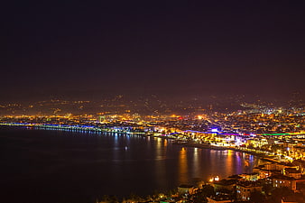 Night cityscape of coastal city with illuminated waterfront and reflections