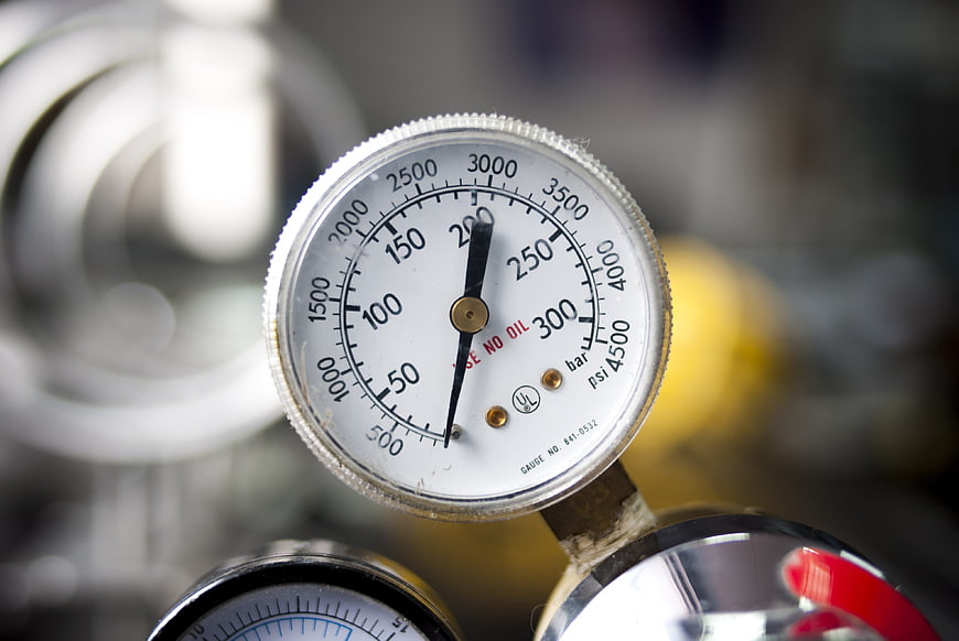 Close-up of industrial pressure gauge with blurred mechanical background