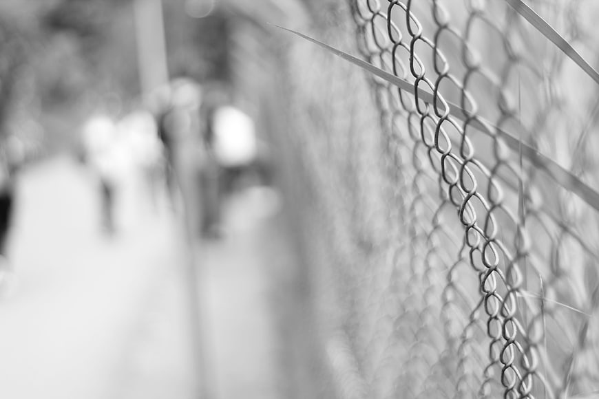 Black and white close-up of chain-link fence with blurred background